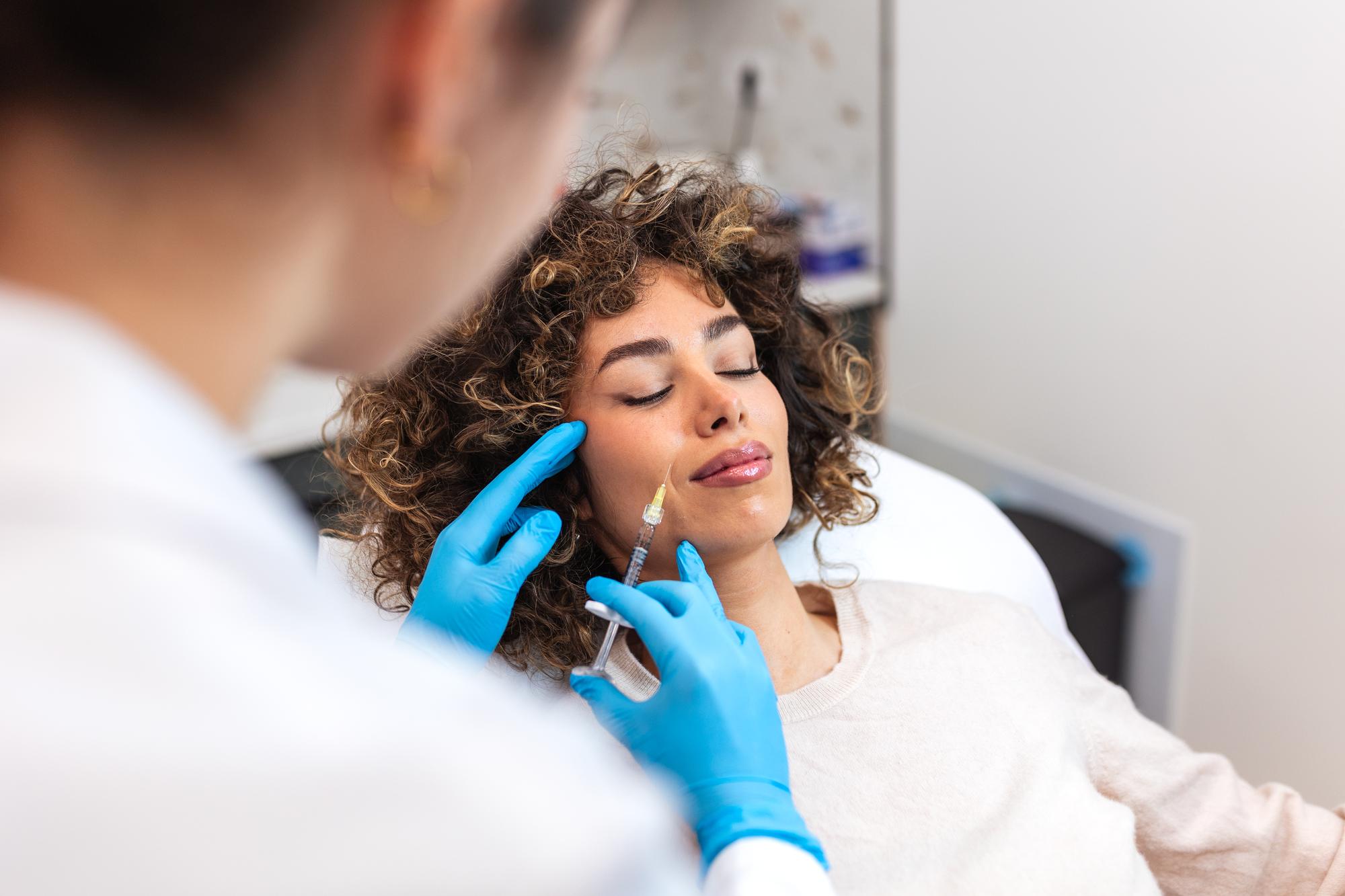 Patient receiving a cosmetic injection treatment along the jaw